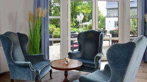A room with three blue armchairs, a wooden table, and a vase with flowers. - Gut Funkenhof (Sundern)