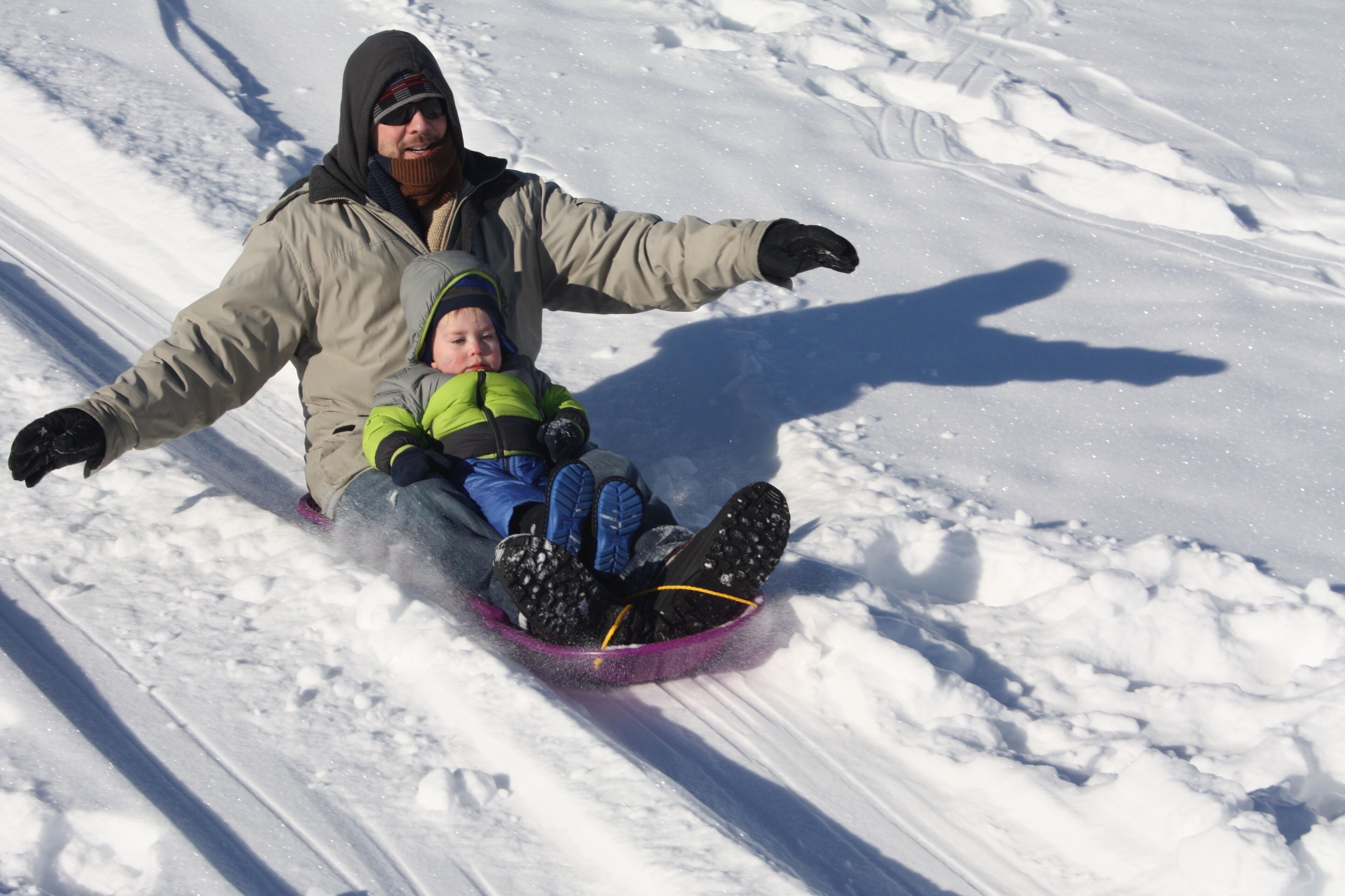 A person sledding with a child on a snowy slope.