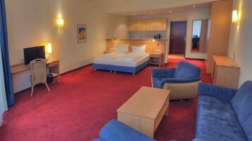 Een hotelkamer met een bed, een bureau met een computer, een stoel, een bank en een kleine tafel.