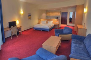 A hotel room with a bed, a desk with a computer, a chair, a sofa, and a small table. - Gut Funkenhof (Sundern)