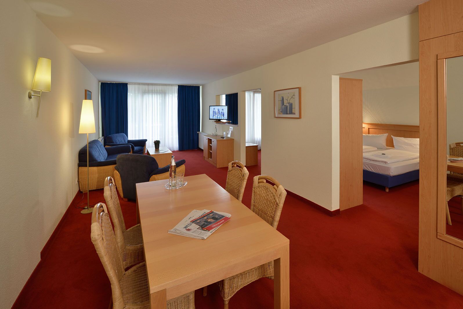 Une chambre d’hôtel comprenant un coin repas, un canapé, une télévision, un lit et une salle de bain.