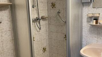 A shower enclosure with a glass door, a white toilet, and a sink with a mirror above it.