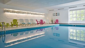 A swimming pool with multiple lounge chairs and a sunlit room with a large window. - Gut Funkenhof (Sundern)
