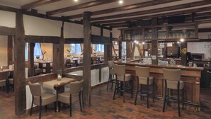 A rustic bar area with wooden beams, a brick floor, and bar stools. - Gut Funkenhof (Sundern)