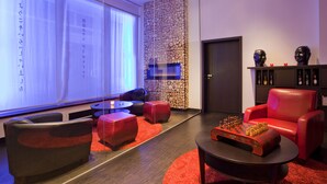 A modern lounge area with leather seating, a chess table, and a stone wall. - Hotel Asahi (Düsseldorf)