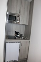 Una cucina compatta con forno a microonde integrato, una macchina da caffè e un lavello.