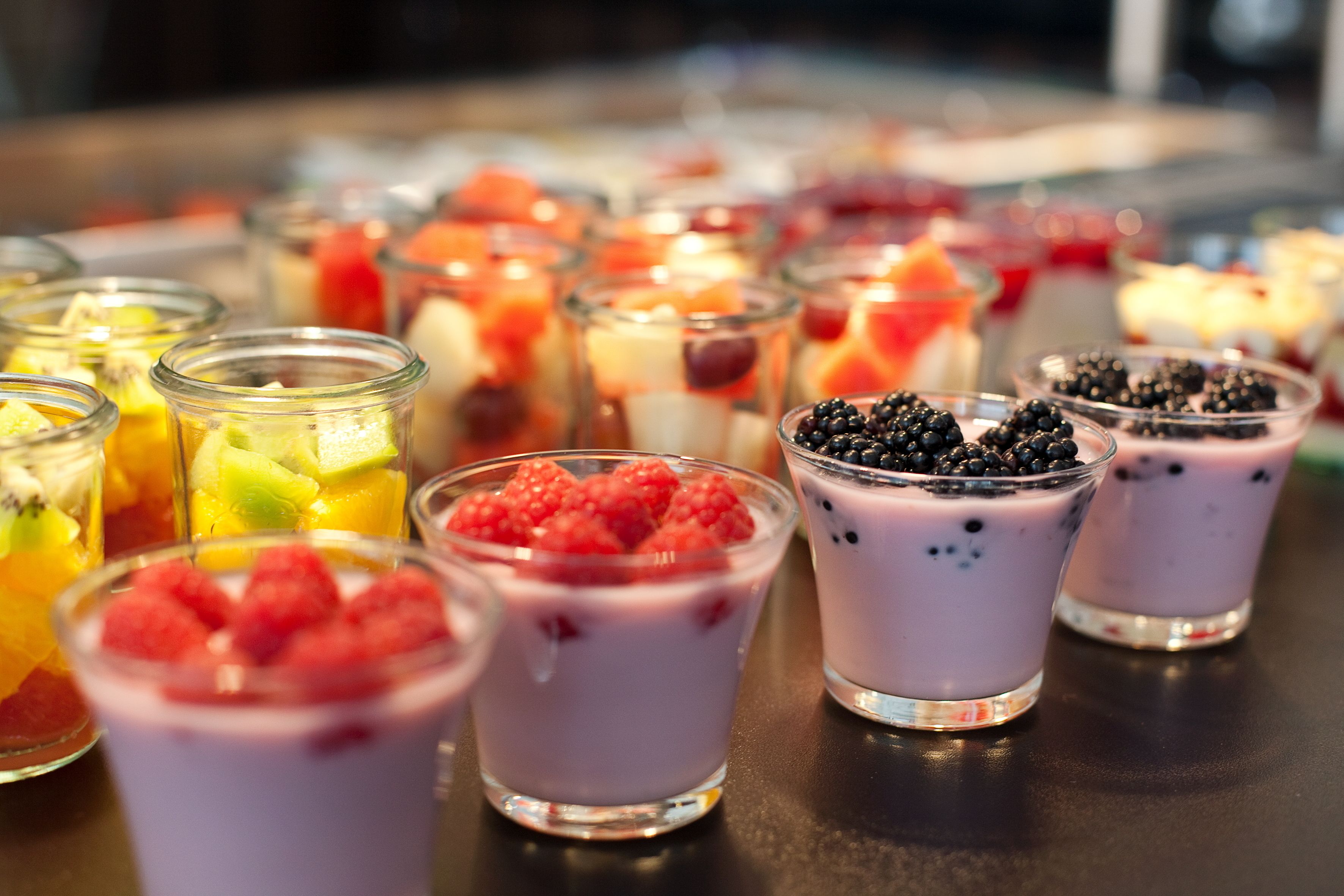 Diversos postres a base de frutas en pequeños vasos de vidrio.