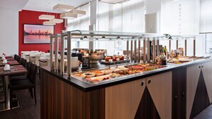 A buffet area with a variety of food items, a red wall with a cityscape painting, and a modern ceiling design. - Hotel Asahi (Düsseldorf)