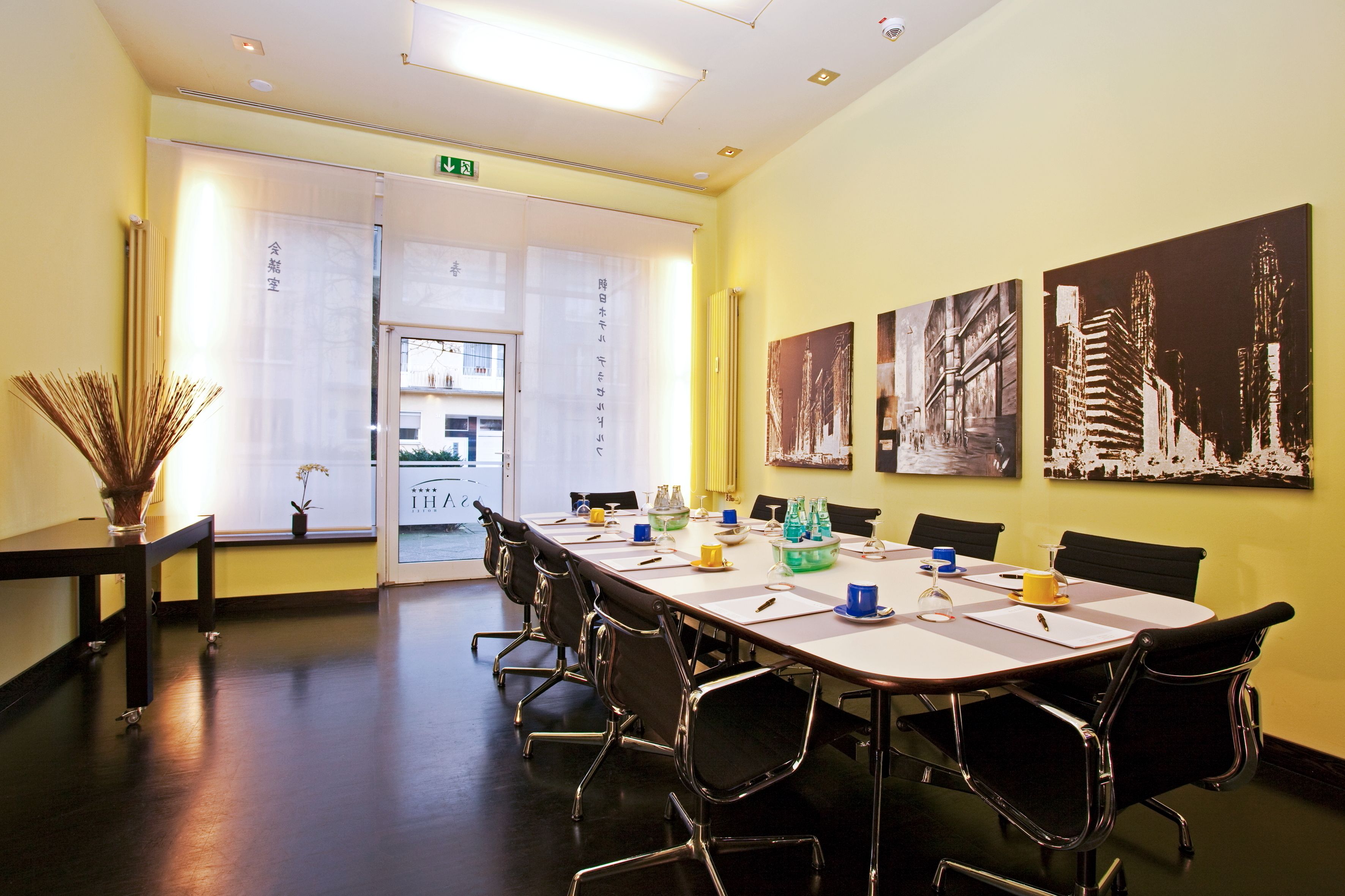 Een vergaderruimte met een lange tafel, zwarte stoelen en kunstwerken aan de muren.
