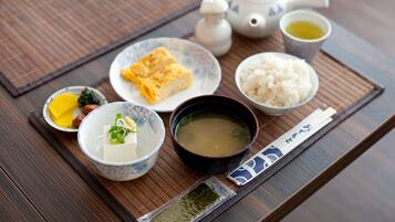 Un montaje tradicional de comida japonesa con tetera, arroz, sopa y varios platos sobre una mesa de madera.