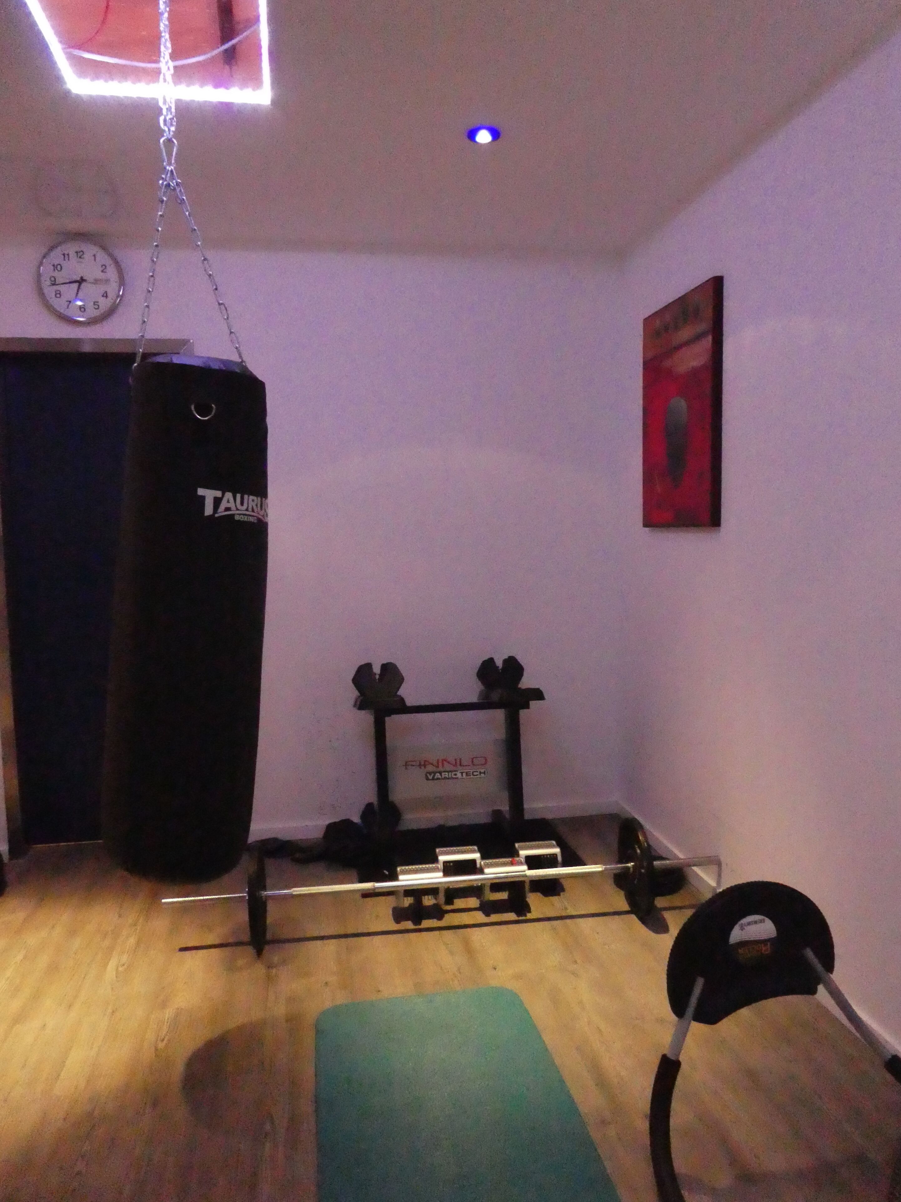 A small gym with a punching bag, weight bench, and dumbbells.