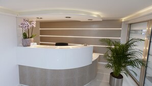 En modern receptionsdisk med en böjd design, en krukväxt och en glasdörr som leder ut.