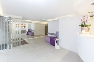 Un interno moderno con una reception, posti a sedere viola e una parete divisoria in vetro.