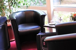 A compact seating area with a black leather chair and a small table with a white object on it. - AKZENT Hotel Schildsheide (Erkrath)