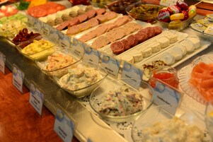 Un buffet con diverse pietanze tra cui carni, formaggi e insalate.
