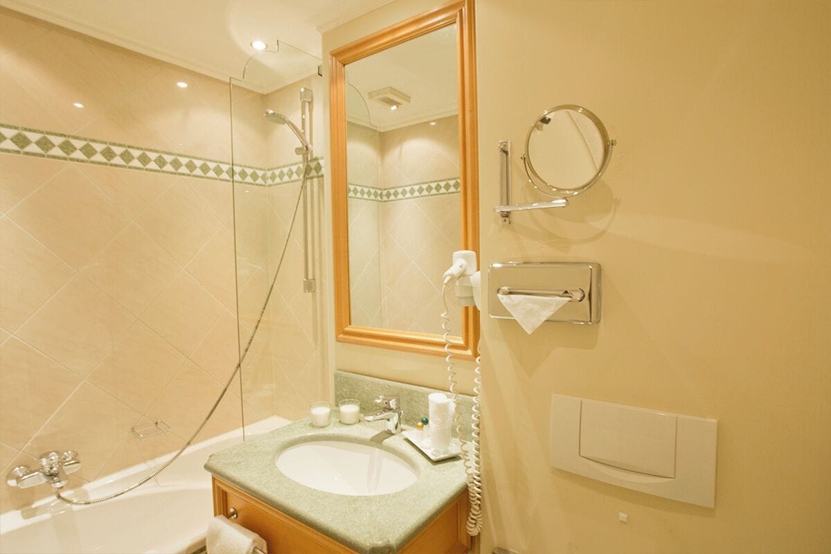 Un baño con bañera, lavamanos, espejo y perchero para toallas.