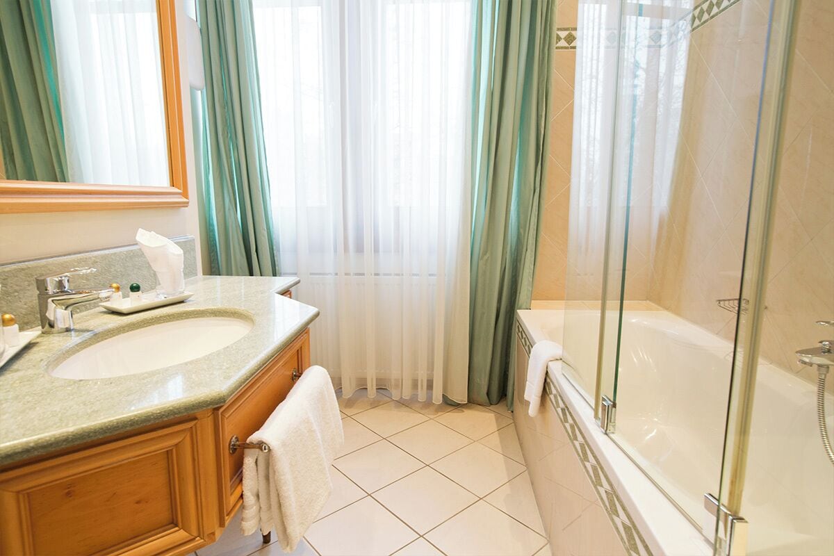 Un baño con lavamanos doble, cabina de ducha con mampara de vidrio y un espejo grande.