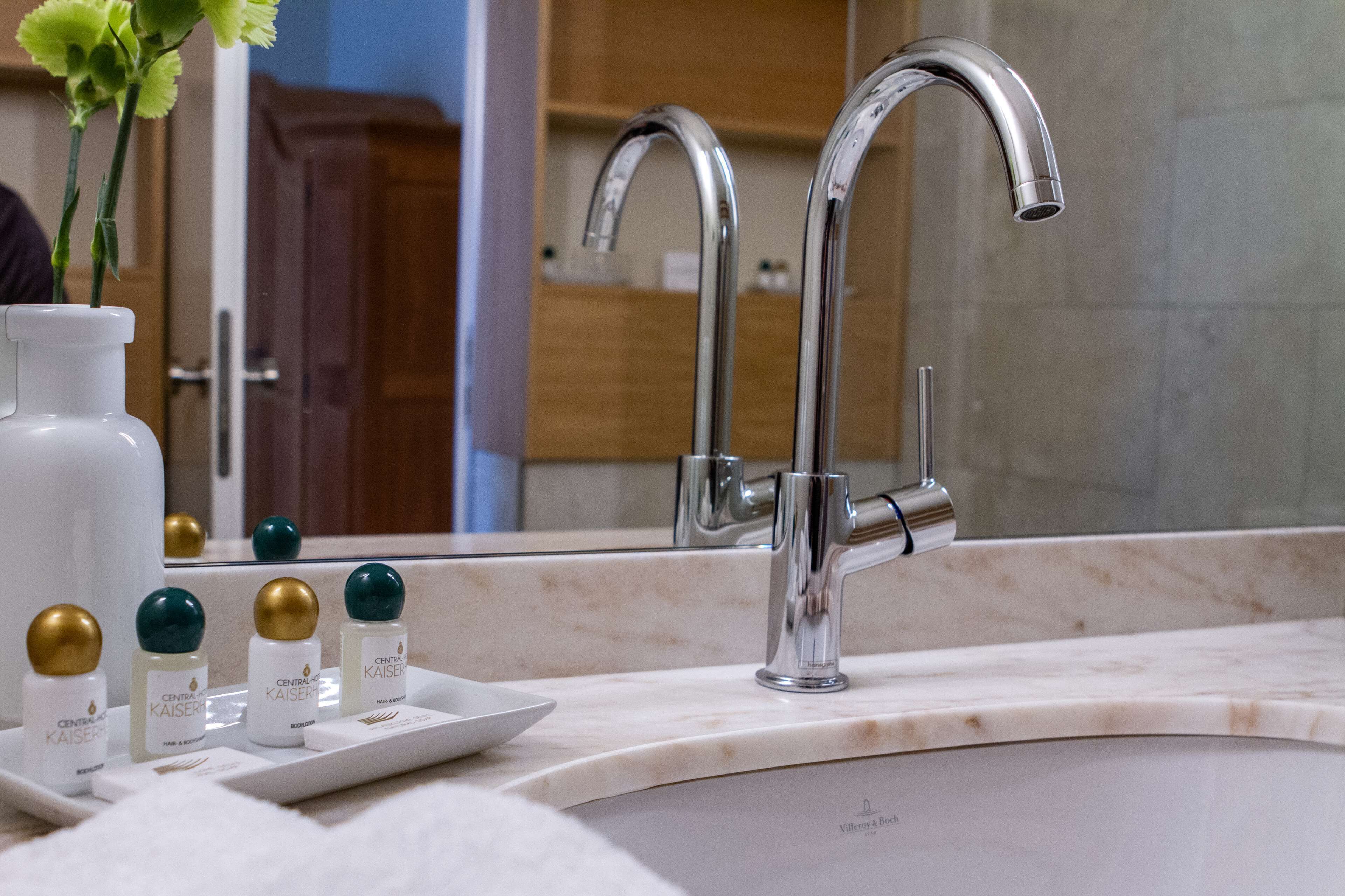 Un meuble-lavabo de salle de bain doté d’un robinet moderne, d’un miroir et d’un plateau contenant des produits de soins pour la peau.