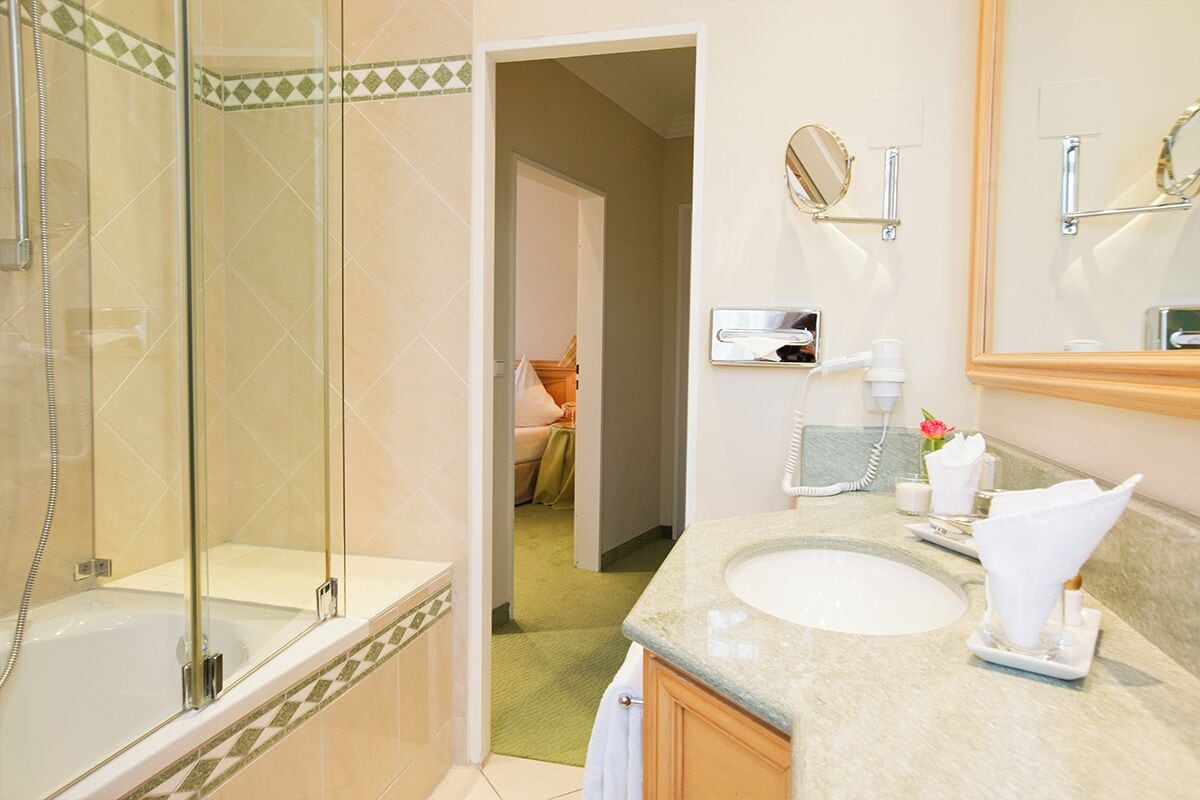 A bathroom with a glass-enclosed shower, a sink with a vanity, and a mirror.