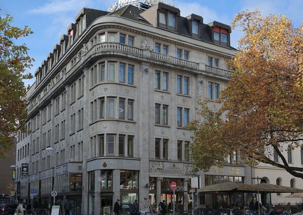 A historic building with multiple stories, featuring a central entrance with a sign for a hotel and a restaurant.