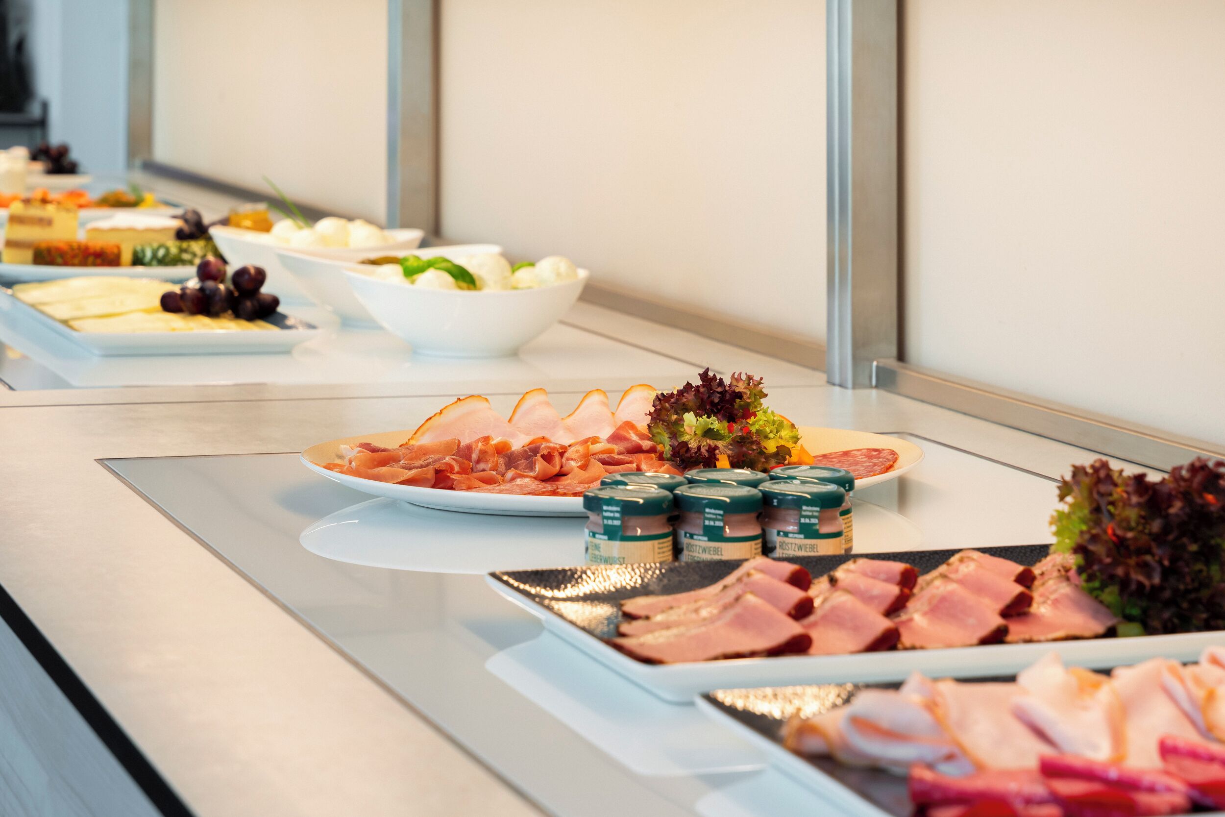 A buffet with various food items including meats, cheeses, and salads.