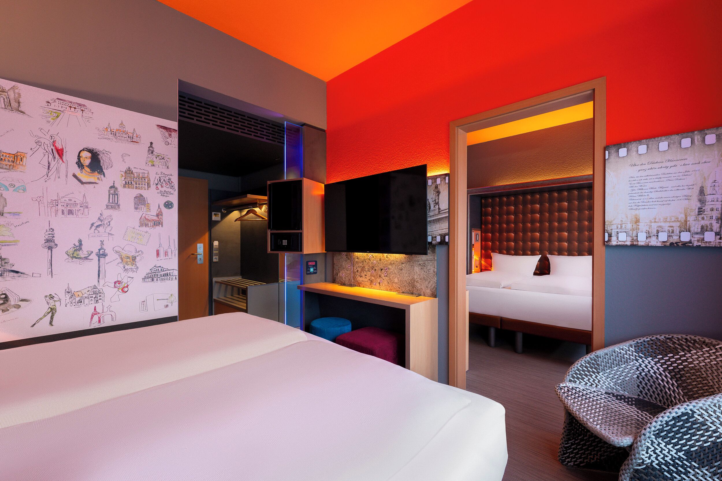 Habitación de hotel con una cama grande, un escritorio, una zona de estar e ilustraciones en la pared.