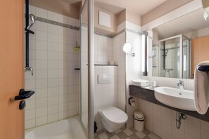 Bathroom features a walk-in shower, toilet, and sink with a mirror.