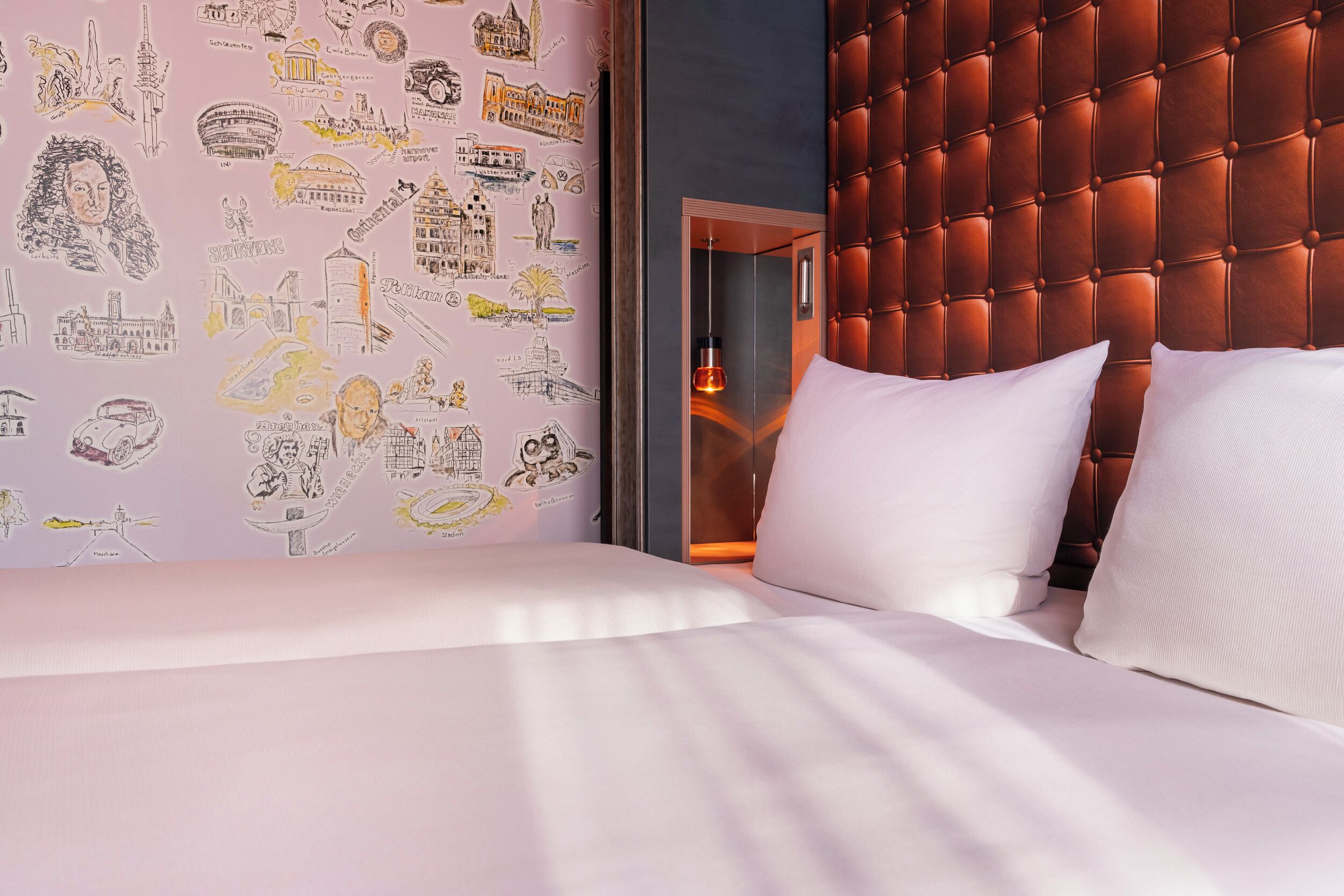 Een hotelkamer met een bed, een gestapeld hoofdbord en een muur met reisillustraties.