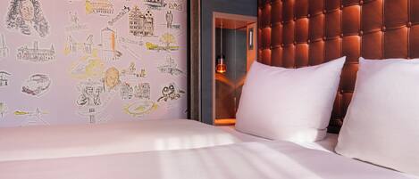 Een hotelkamer met een bed, een gestapeld hoofdbord en een muur met reisillustraties.
