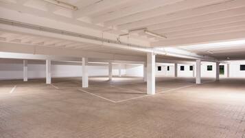 Un espacio interior amplio con suelo de ladrillo, pilares blancos y un techo alto con conductos expuestos.