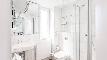 A modern bathroom with a sink, mirror, toilet, and glass shower enclosure.