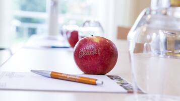 Una mesa con una manzana roja, un bolígrafo y una jarrón de vidrio.