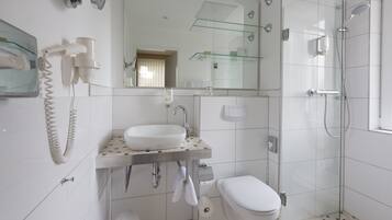 Un baño moderno con cabina de ducha de vidrio, lavabo blanco y retrete.