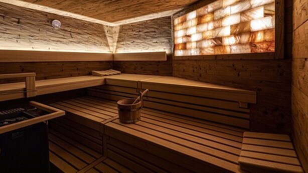 Una sauna de madera con bancos y un balde.