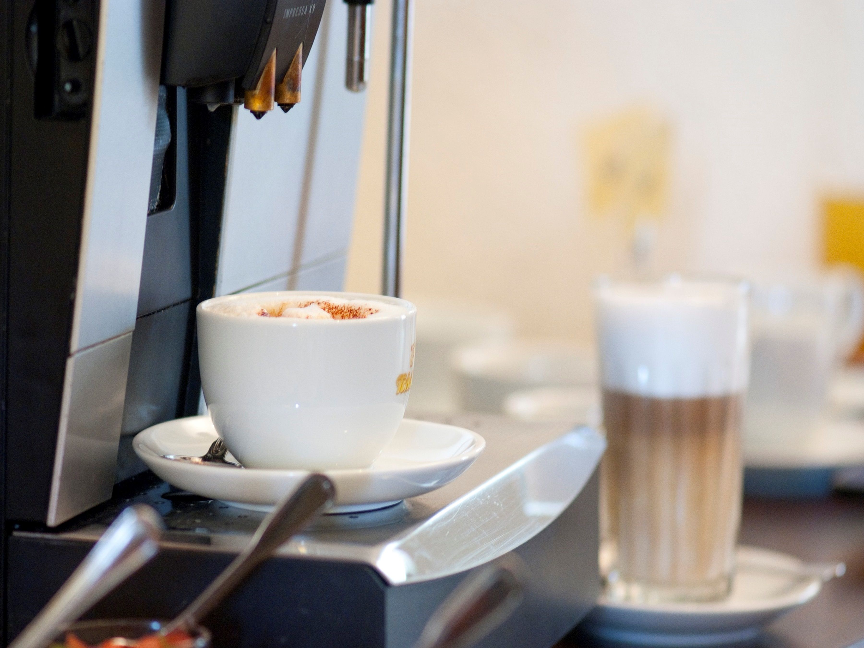 A coffee machine with a cup and saucer, and a glass of beer on a table.