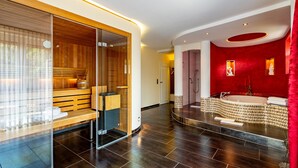 A modern spa with a sauna, a steam room, and a large red-tiled jacuzzi. - Hotel Heide Kröpke (Essel)