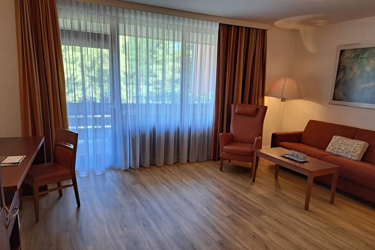 Ein Zimmer mit Esstisch, zwei Stühlen, einer Couch, einem Couchtisch und einer Lampe.