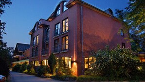 A multi-story brick building with balconies and large windows, surrounded by greenery. - Hotel Heide Kröpke (Essel)