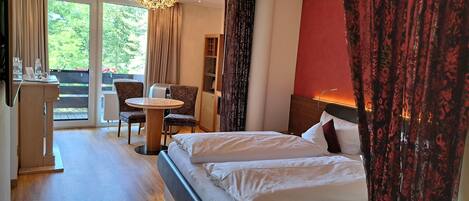 Ein Hotelzimmer mit Bett, Schreibtisch, Stuhl und Blick ins Freie.