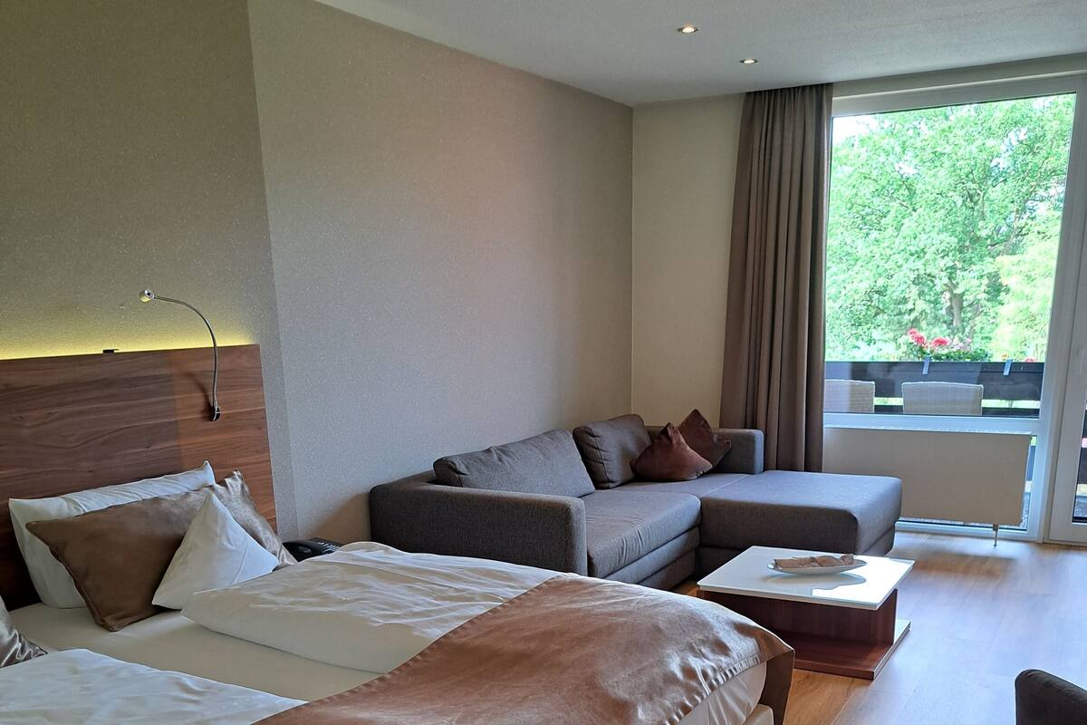 Ein modernes Hotelzimmer mit zwei Betten, einem Schlafsofa und einem kleinen Tisch.