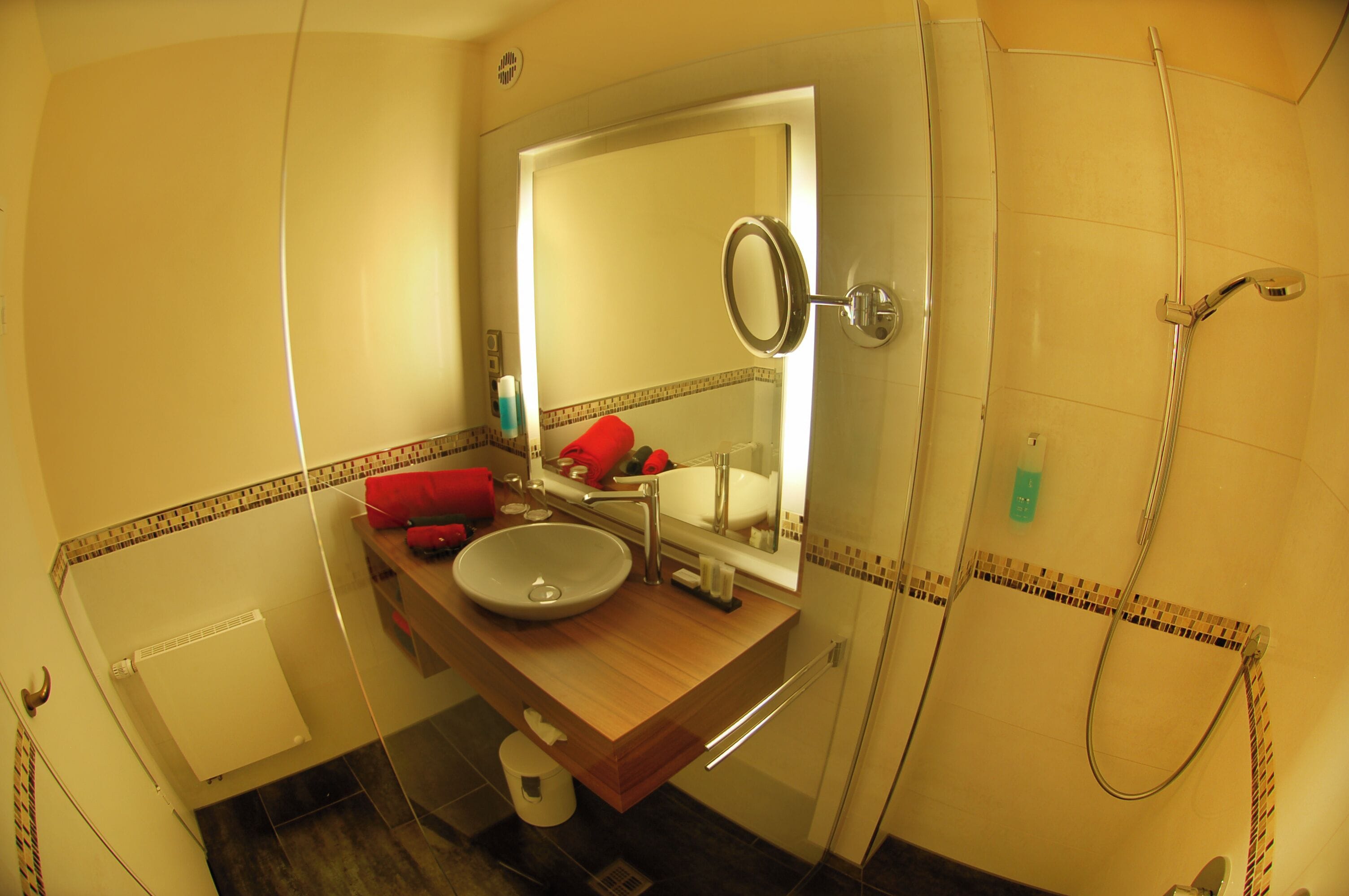 Ein Badezimmer mit einem Holzbadezimmer-Möbelstück, einem großen Spiegel, einem Waschbecken und einer Dusche.