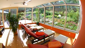 A sunlit room with large windows, a ceiling fan, and a potted plant. - Hotel Heide Kröpke (Essel)