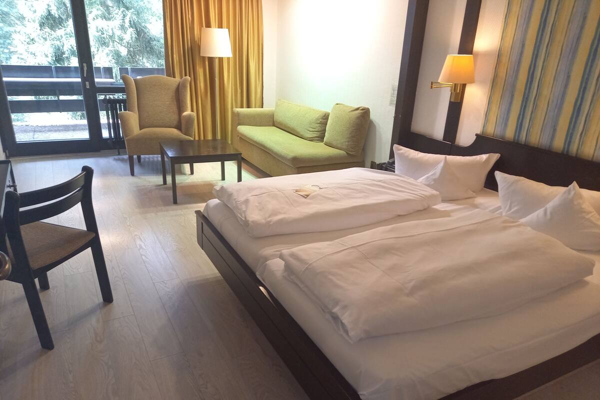 Ein Hotelzimmer mit einem Bett, zwei Sessel, einer Couch und einer Lampe.