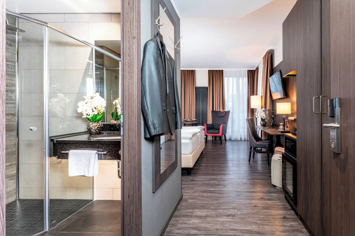 Een moderne hotelkamer met een douche, een bed, een bureau en een eethoek.