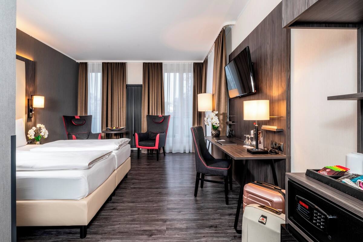 Een hotelkamer met een bed, een bureau met stoel, een televisie en een minibar.