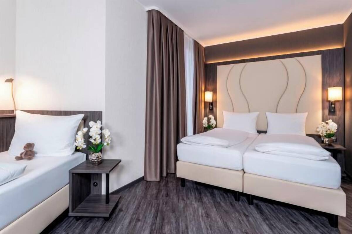 Een hotelkamer met een tweepersoonsbed, nachtkastje en lamp.