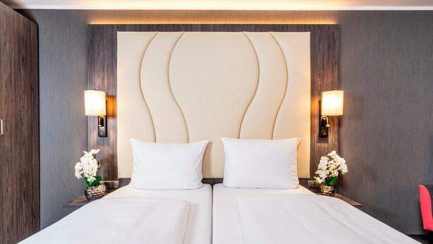 Una habitación de hotel con una cama doble, dos lámparas de noche y una silla roja.