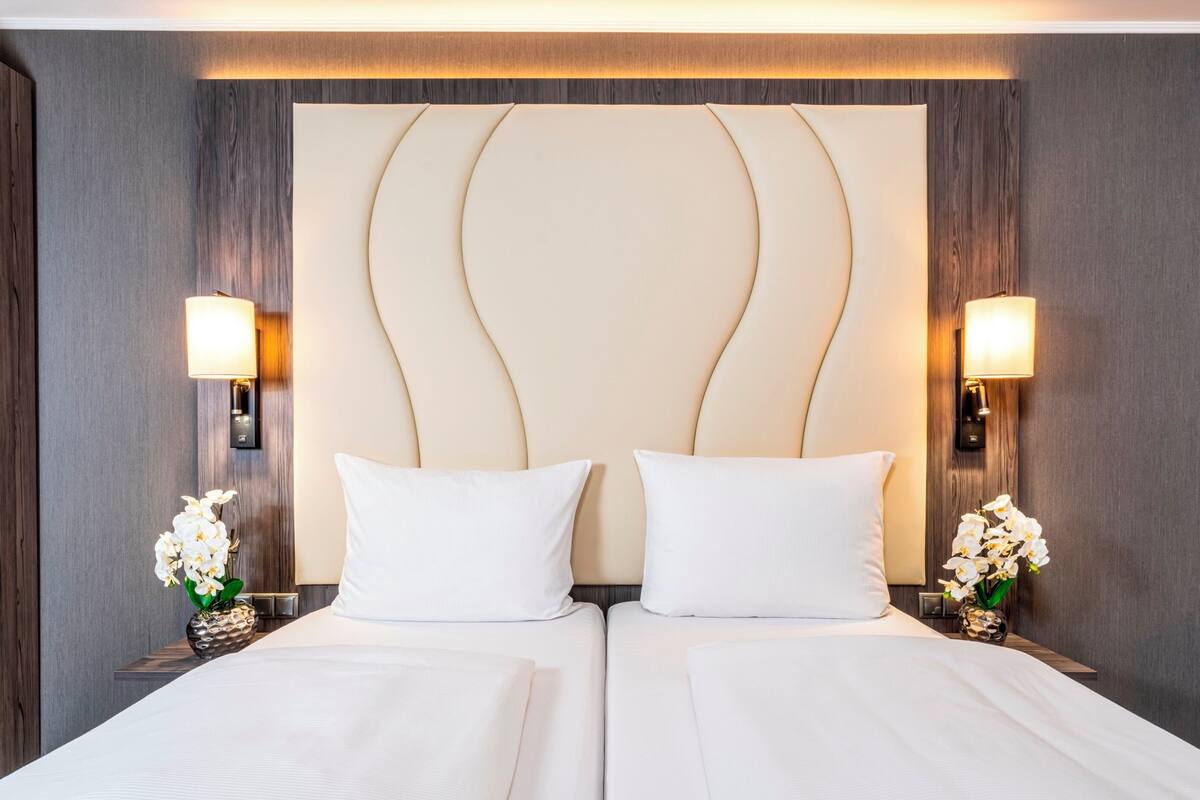 Een hotelkamer met een tweepersoonsbed, twee bedlampen en een rode stoel.