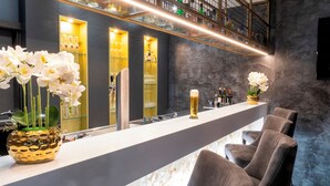 Un área de bar moderna con una barra larga, taburetes y orquídeas blancas decorativas.