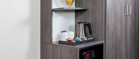 Un miniibar con cafetera, hervidor de agua y pequeño refrigerador.